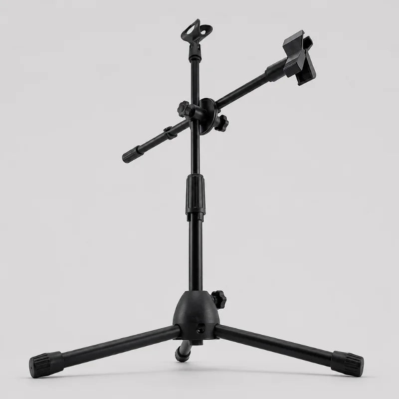 Trépied micro noir avec bras horizontal incline vers droite, clip téléphone noir et support micro en haut, trois pieds déployés, vue trois quarts sur fond gris