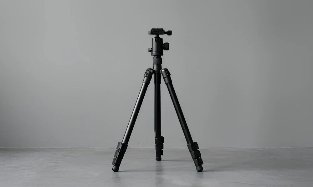 Photographe utilisant un trépied vidéo pour filmer une scène en extérieur