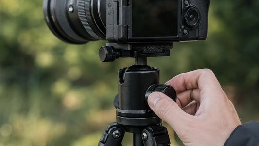Photographe réglant la rotule à boule d'un trépied avec appareil photo