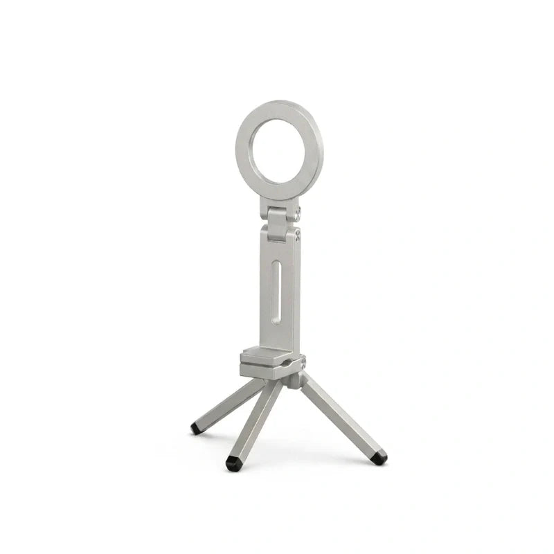 Mini trépied téléphone argenté avec anneau magnétique circulaire en haut et quatre petits pieds noirs, sur fond blanc