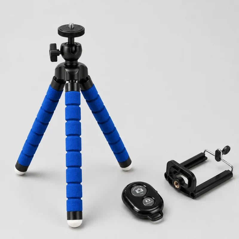 Trépied flexible bleu déployé sur fond gris avec tête rotative noire, télécommande Bluetooth noire et support téléphone noir posés a côté