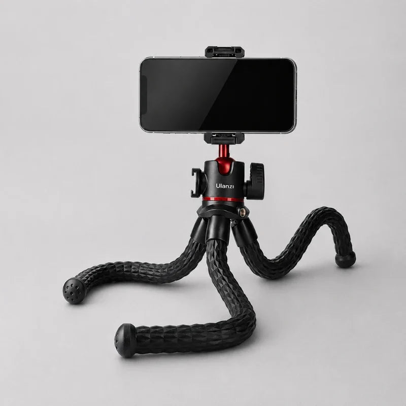 Trépied flexible noir avec smartphone fixé en mode paysage, pieds flexibles posés à plat sur fond gris clair