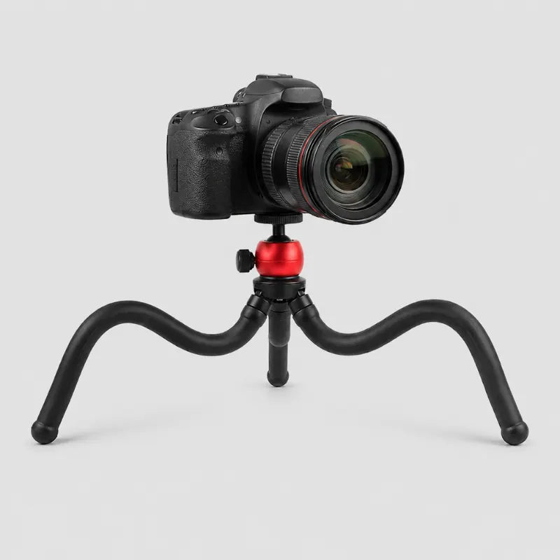 Trépied poulpe flexible rouge et noir avec appareil photo reflex DSLR noir monté sur la rotule, jambes souples etalees sur fond gris clair