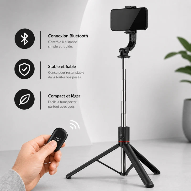 Trépied noir pour téléphone avec smartphone fixé et télécommande Bluetooth dans une main, fond intérieur lumineux